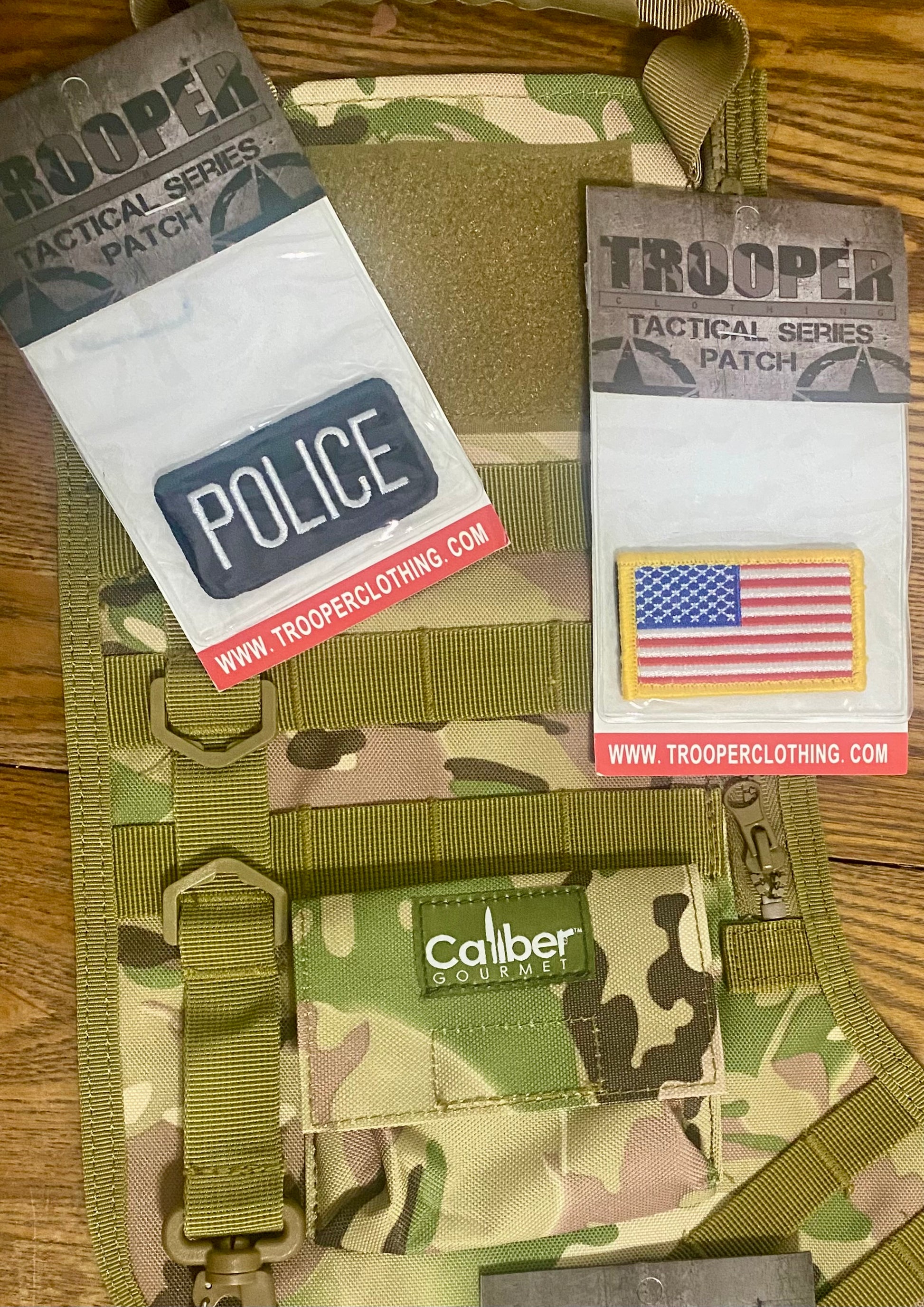 Camouflage tactical patch with 'Police' and 'Trooper' patches on a wooden surface.