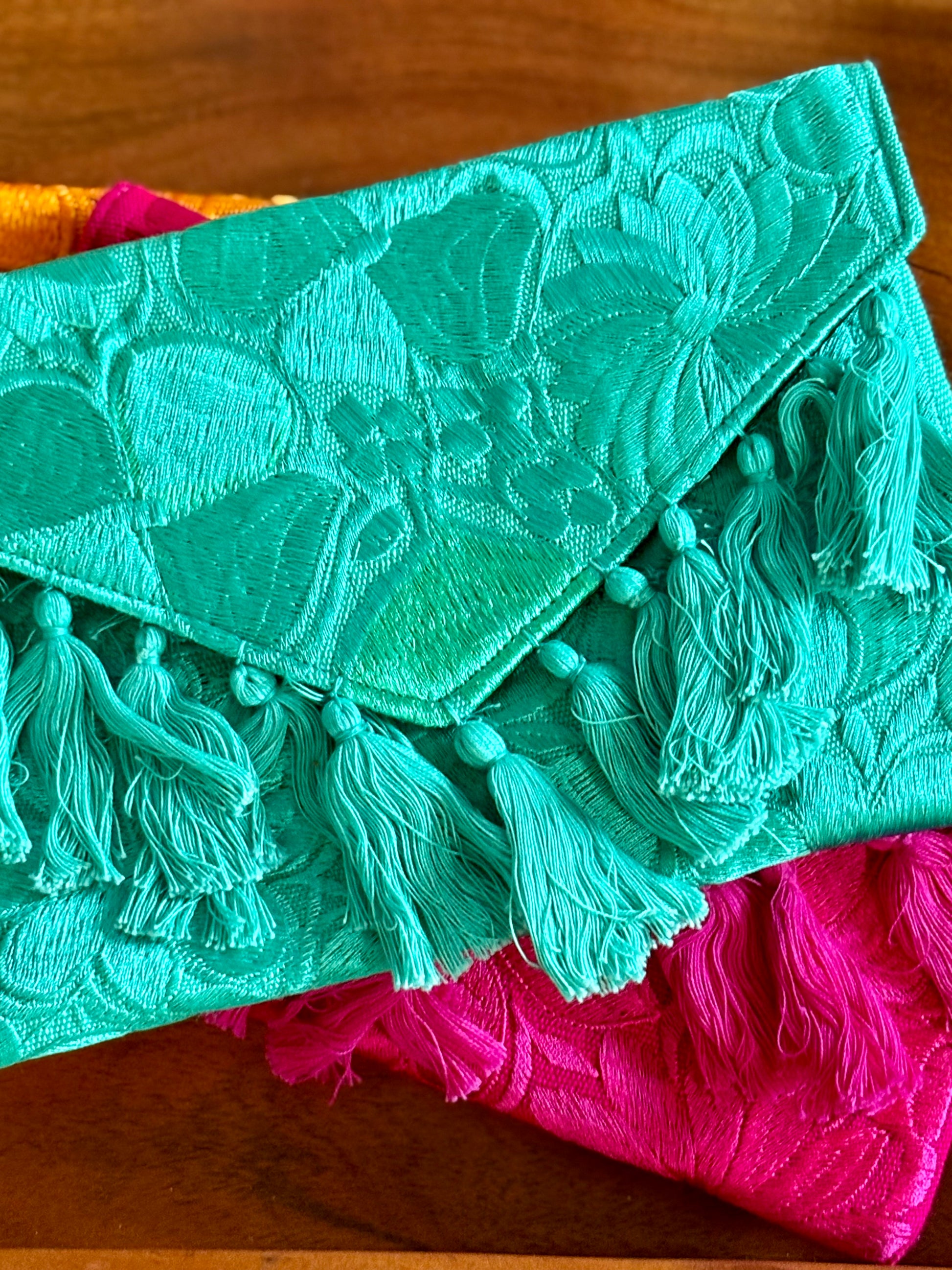 Turquoise clutch with tassels on a wooden surface
