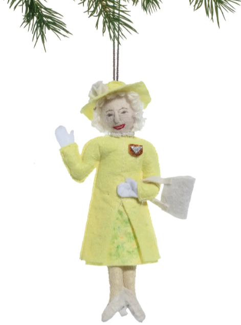 Christmas ornament of queen elizabeth in a yellow outfit with a hat and gloves, hanging from a tree.